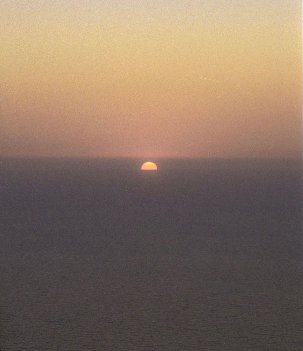 Sun setting into a calm sea at dusk