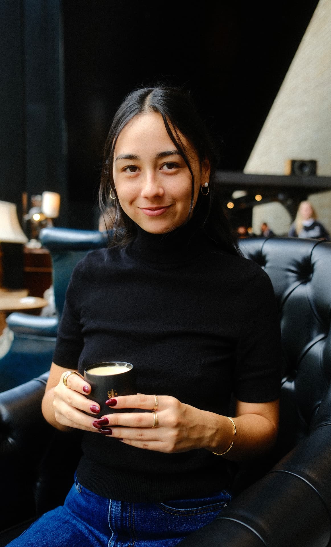 Kira sitting in an armchair holding a cup of coffee